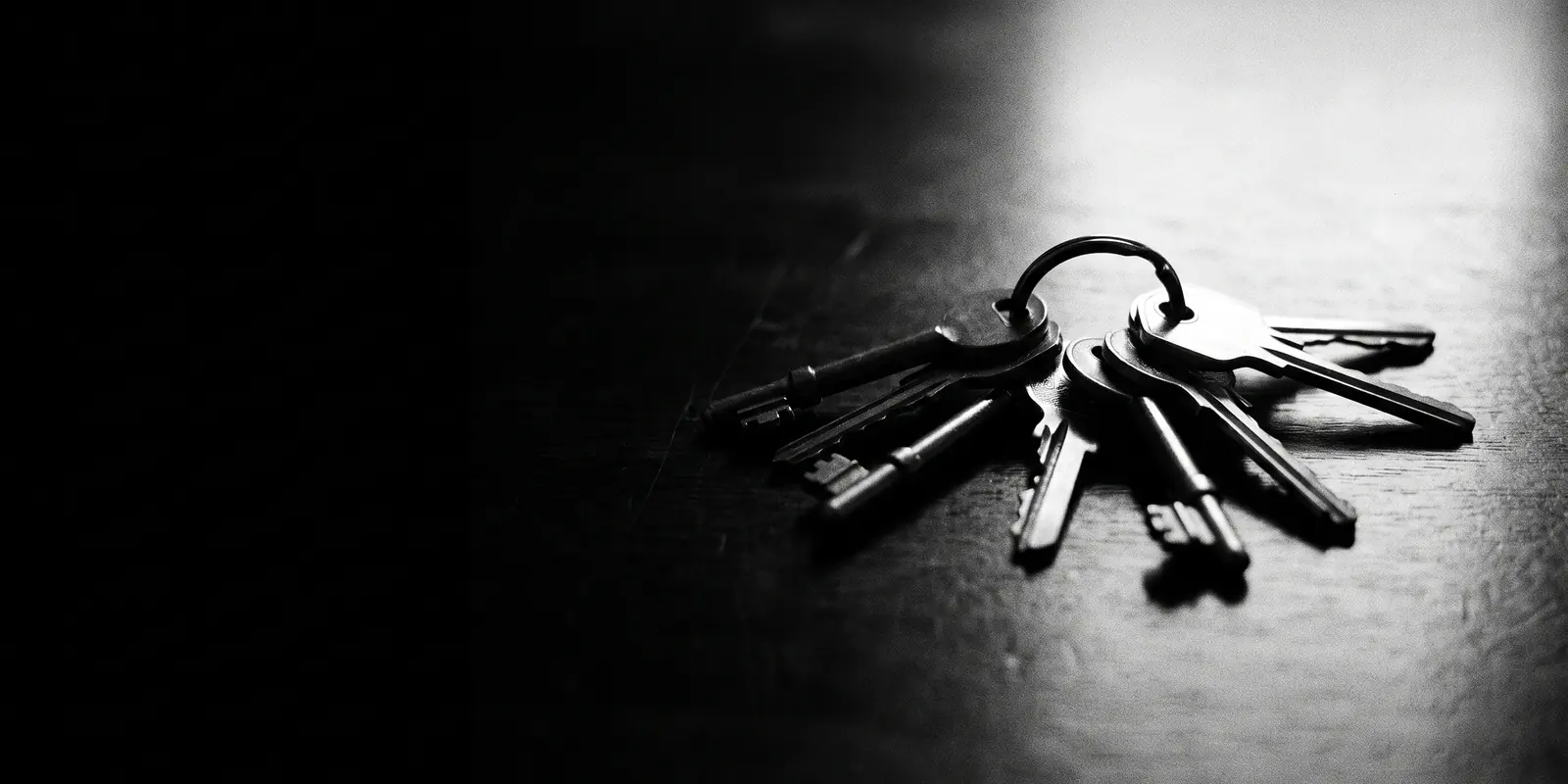 A bunch of keys lies in raking light on a dark table — an image for the trust you place in an IT partner: the keys to your whole business.