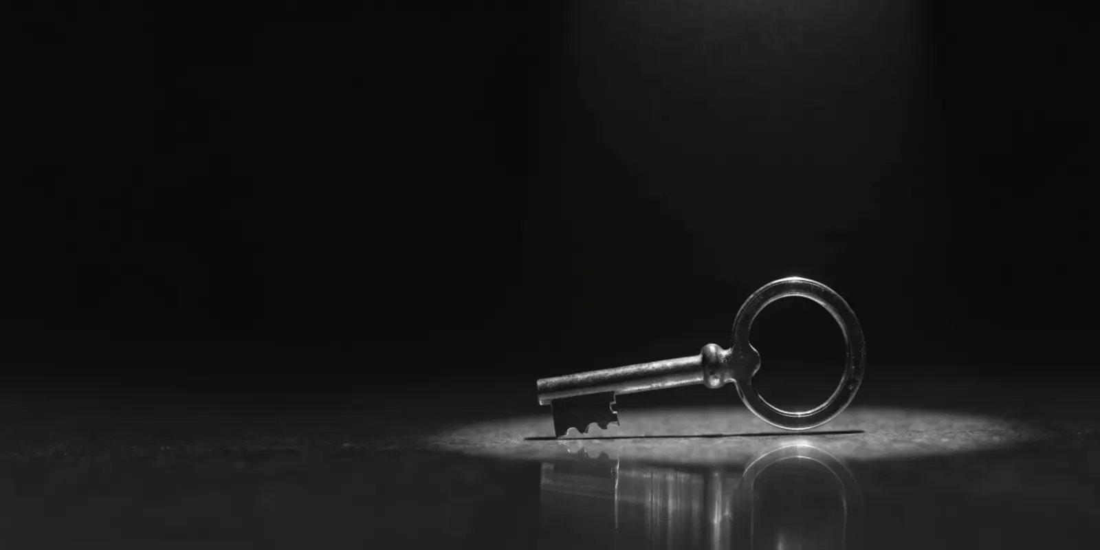 Close-up of an old-fashioned key in a lock, bright spotlight against a dark background, symbolising digital access security