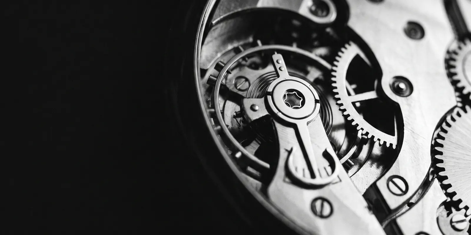 Macro-opname van een fijn uurwerk met in elkaar grijpende tandwielen in strijklicht — beeld voor automatisering die het repetitieve werk betrouwbaar op de achtergrond doet.